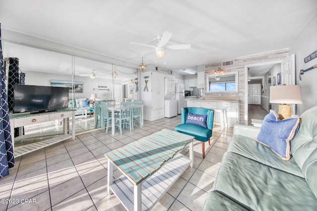 living room featuring washer / clothes dryer, ceiling fan, and light tile patterned flooring