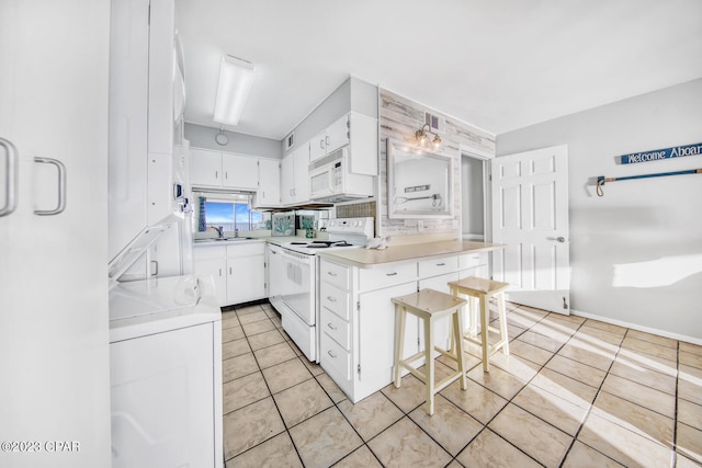 kitchen featuring a kitchen breakfast bar, white cabinets, white appliances, washer / dryer, and sink