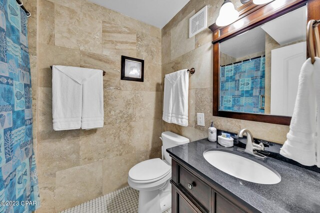 bathroom with a shower with shower curtain, tile patterned flooring, toilet, tile walls, and vanity