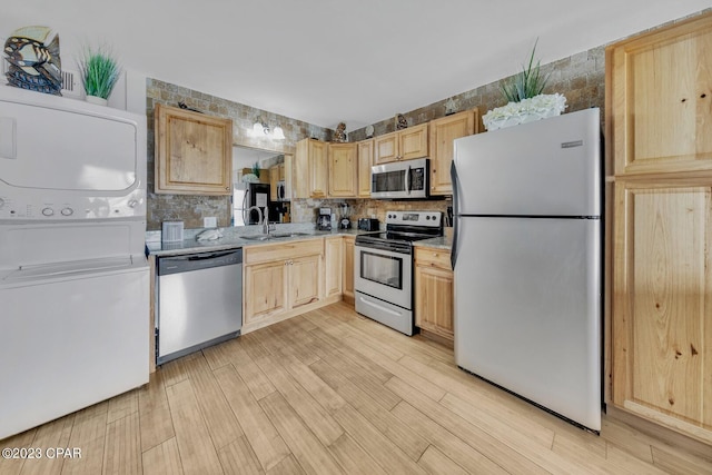 kitchen with light wood-type flooring, light brown cabinetry, stainless steel appliances, and stacked washer / drying machine