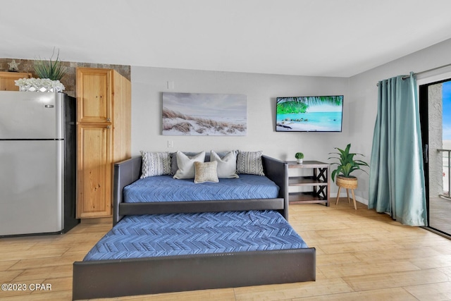 bedroom with light hardwood / wood-style flooring and stainless steel refrigerator