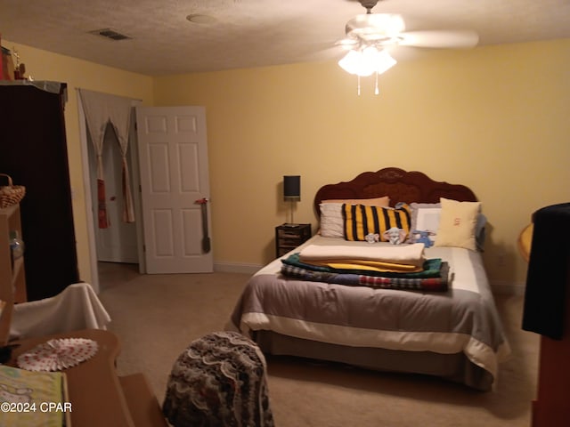 carpeted bedroom featuring ceiling fan and a textured ceiling