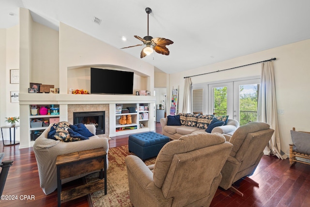 living room with lofted ceiling, dark wood-type flooring, french doors, ceiling fan, and a tiled fireplace