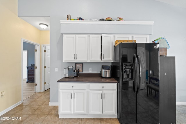 kitchen featuring lofted ceiling, white cabinetry, black refrigerator with ice dispenser, and light tile patterned flooring