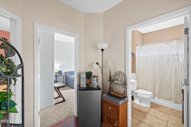 bathroom featuring tile patterned flooring, toilet, and shower / tub combo