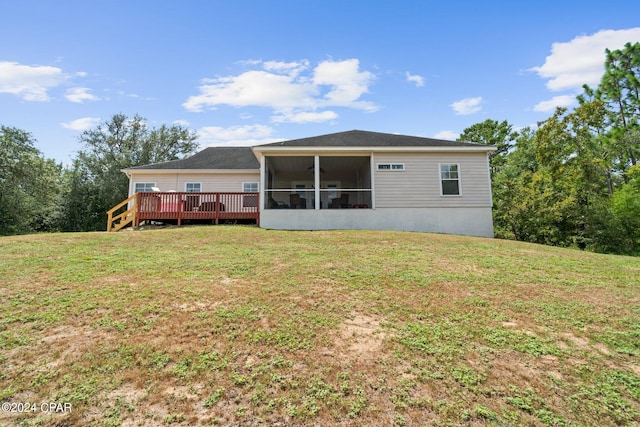 rear view of house with a lawn, a sunroom, and a wooden deck