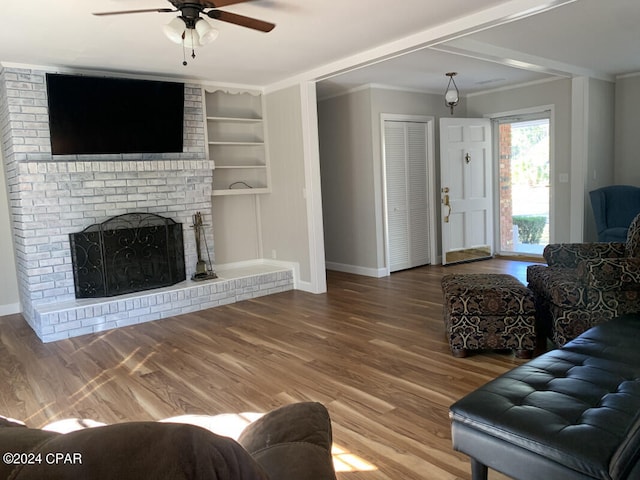 living room featuring brick wall, wood-type flooring, a brick fireplace, and ceiling fan