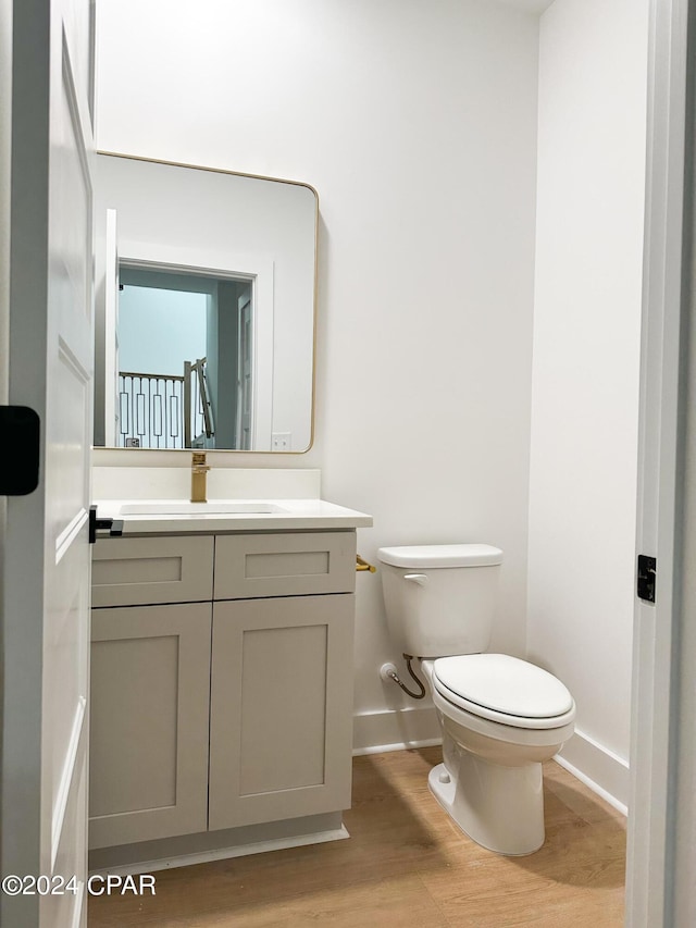 bathroom featuring wood-type flooring, vanity, and toilet