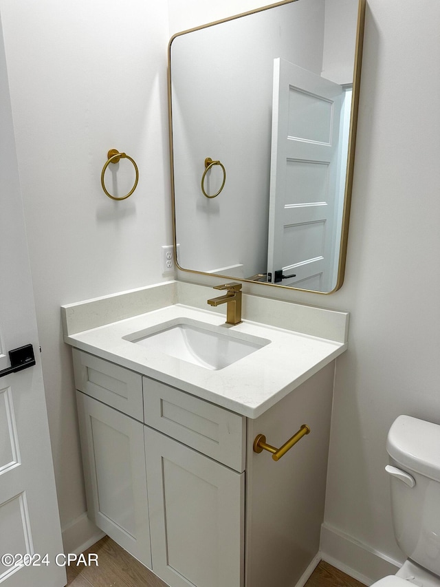 bathroom featuring vanity, toilet, and hardwood / wood-style flooring