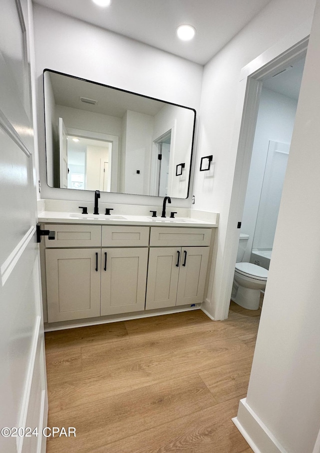 bathroom with hardwood / wood-style floors, vanity, and toilet