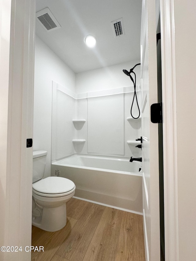 bathroom with tub / shower combination, hardwood / wood-style floors, and toilet