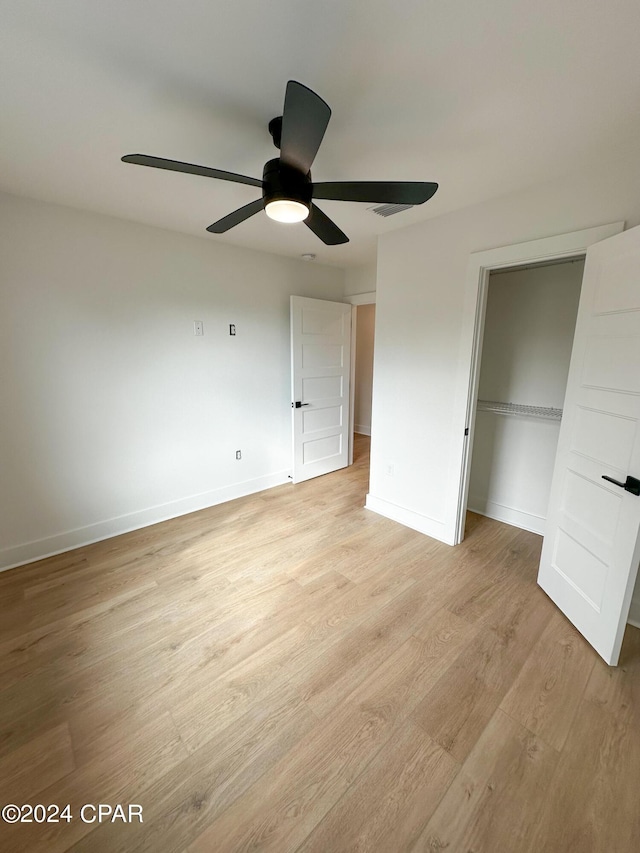 unfurnished bedroom with light hardwood / wood-style floors, ceiling fan, and a closet