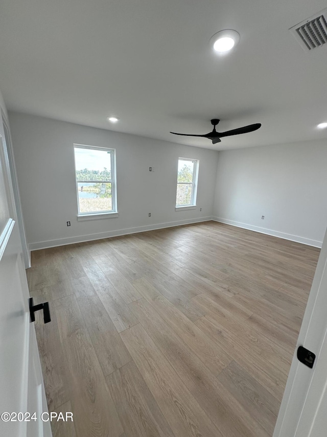 spare room featuring light wood-type flooring, ceiling fan, and a wealth of natural light