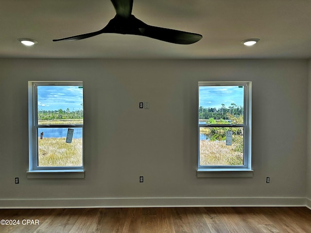 spare room with a wealth of natural light, a water view, and hardwood / wood-style floors