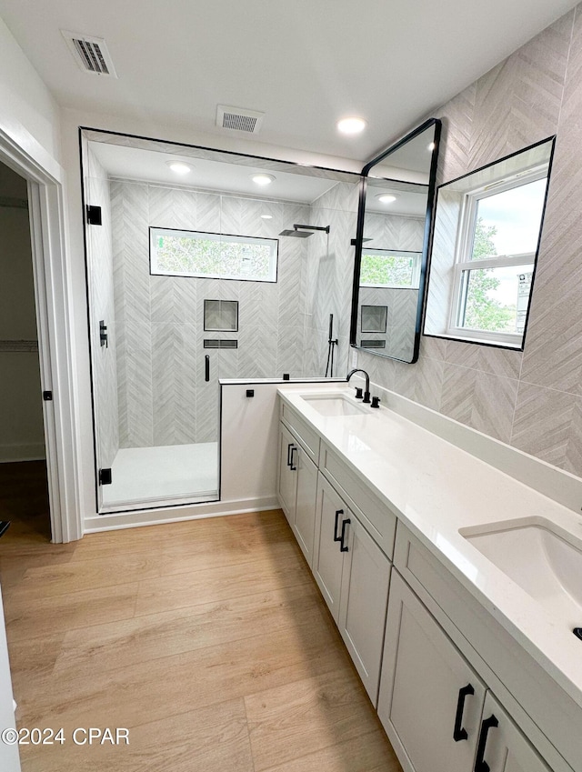 bathroom with wood-type flooring, vanity, and an enclosed shower