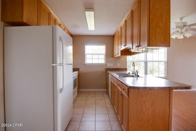 kitchen with white fridge, kitchen peninsula, sink, ceiling fan, and light tile patterned flooring