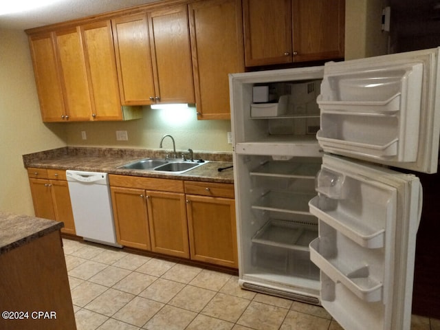 kitchen with light tile patterned floors, white appliances, and sink