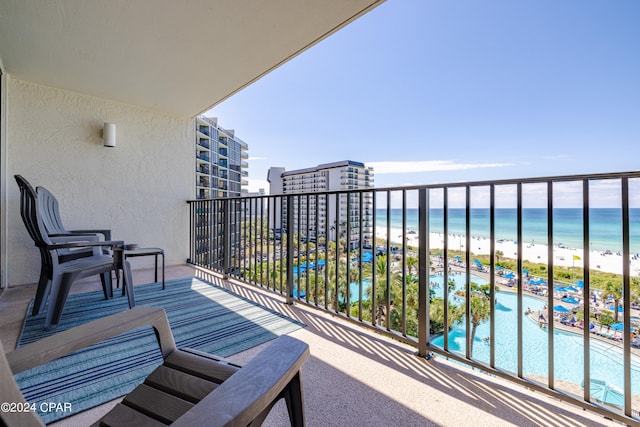 balcony with a water view, a view of the beach, and a community pool