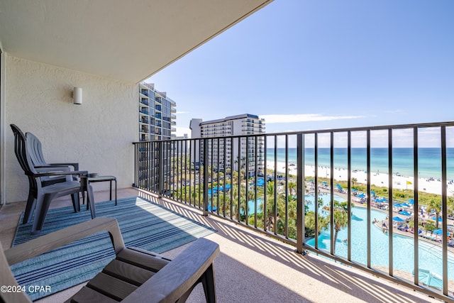 balcony with a water view and a view of the beach