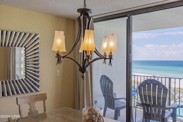 interior space with a water view, a view of the beach, and a textured ceiling