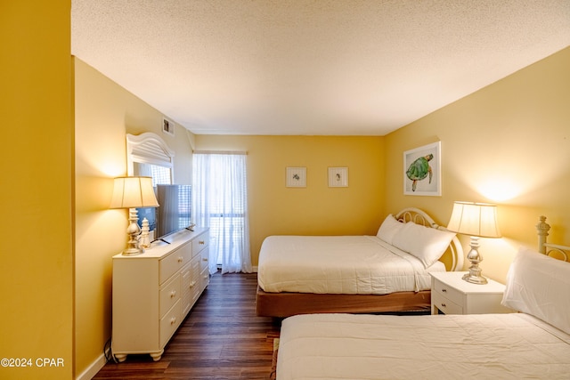 bedroom featuring a textured ceiling, dark wood-style flooring, visible vents, and baseboards