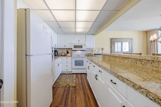 kitchen featuring white appliances, dark wood finished floors, a paneled ceiling, white cabinetry, and backsplash