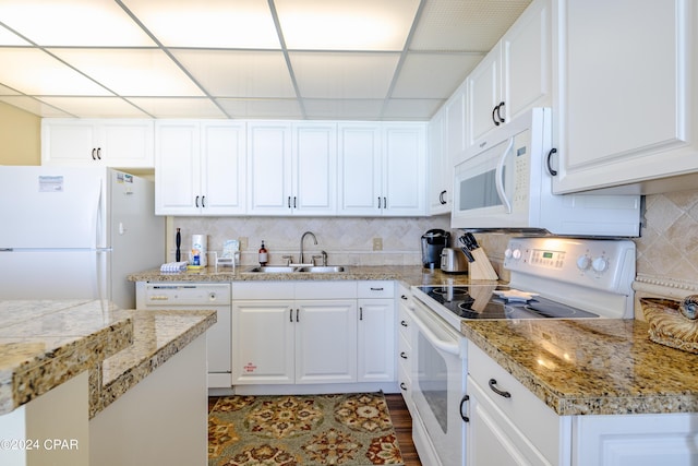 kitchen with white appliances, white cabinetry, decorative backsplash, and a sink