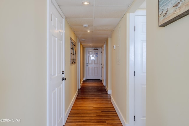 corridor featuring baseboards, a drop ceiling, and wood finished floors