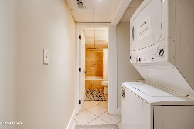 laundry area featuring light tile patterned floors, laundry area, baseboards, visible vents, and stacked washer / drying machine