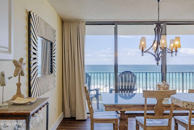 dining area with dark wood-style floors, a chandelier, a water view, and a textured ceiling