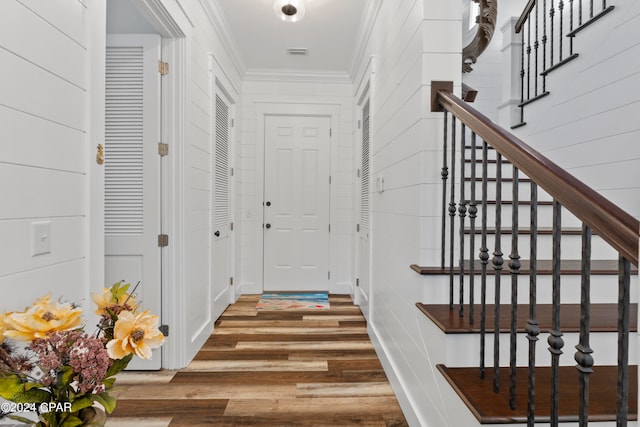 foyer entrance with crown molding and hardwood / wood-style floors