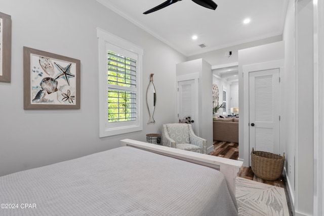 bedroom with ceiling fan, a closet, crown molding, and wood-type flooring