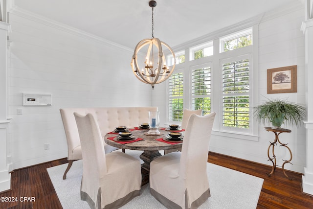 dining room featuring wood walls, ornamental molding, a chandelier, and dark hardwood / wood-style flooring