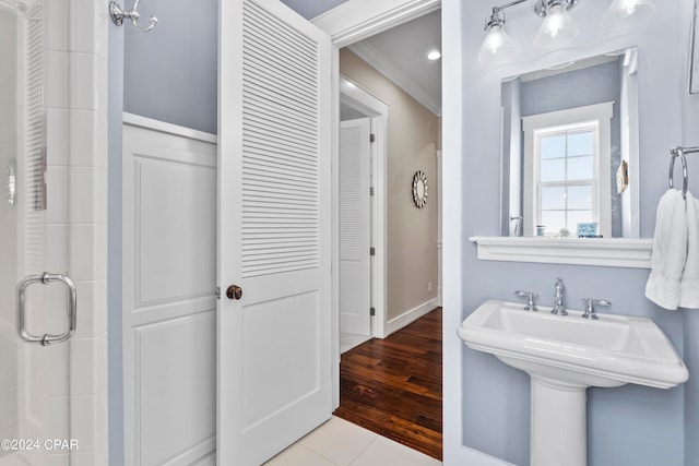 bathroom featuring a shower with shower door, crown molding, and hardwood / wood-style flooring