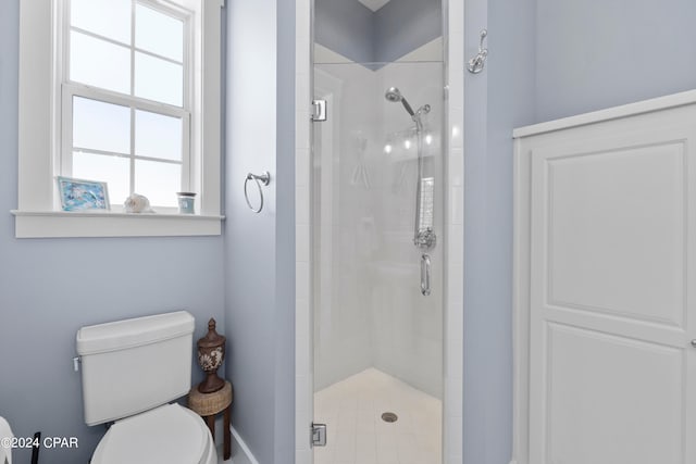 bathroom featuring a shower with door and toilet