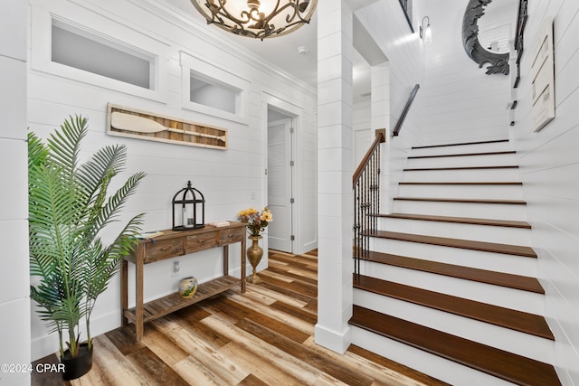 stairway featuring crown molding, a chandelier, and hardwood / wood-style flooring