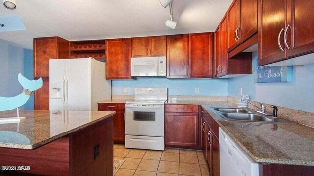 kitchen featuring stone countertops, white appliances, track lighting, and sink