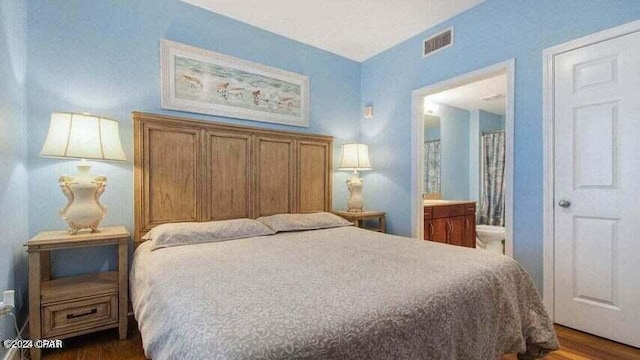 bedroom with connected bathroom and dark wood-type flooring