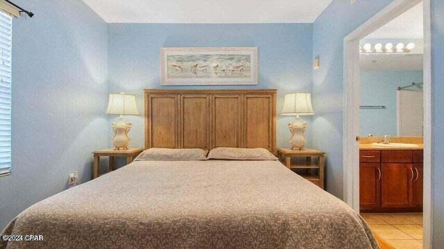 bedroom with light tile patterned floors, sink, and connected bathroom