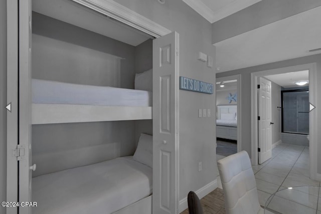 bedroom featuring ornamental molding, light tile patterned flooring, and ensuite bathroom