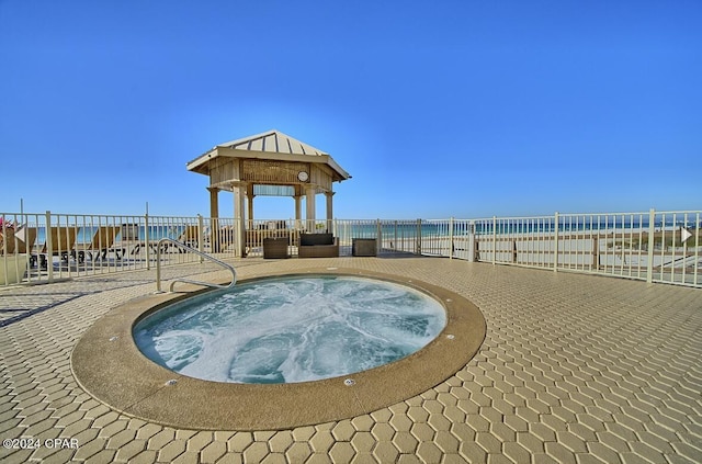 view of home's community with a jacuzzi, a view of the beach, a patio area, a gazebo, and a water view