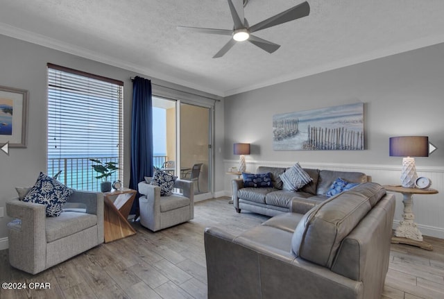 living room with a textured ceiling, crown molding, ceiling fan, and light hardwood / wood-style flooring