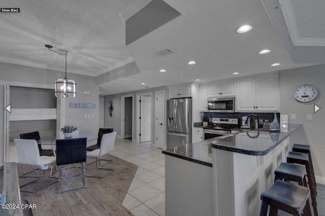 kitchen with decorative backsplash, light tile patterned flooring, white cabinets, pendant lighting, and stainless steel appliances