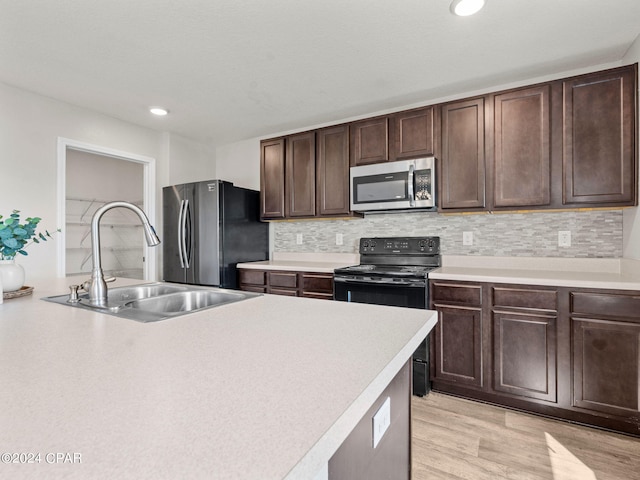 kitchen with light wood-type flooring, sink, decorative backsplash, appliances with stainless steel finishes, and dark brown cabinetry