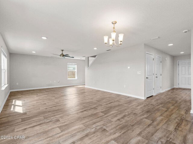 unfurnished living room featuring ceiling fan with notable chandelier and wood-type flooring