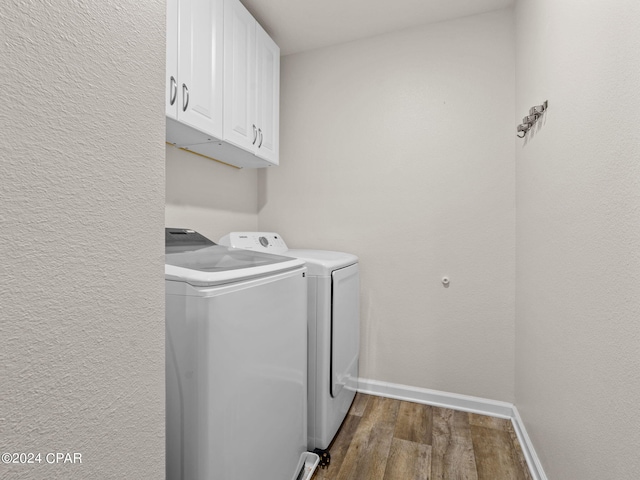 washroom featuring dark wood-type flooring, cabinets, and washing machine and dryer