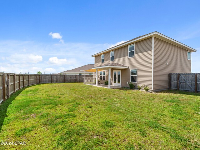 rear view of house with a lawn and a patio