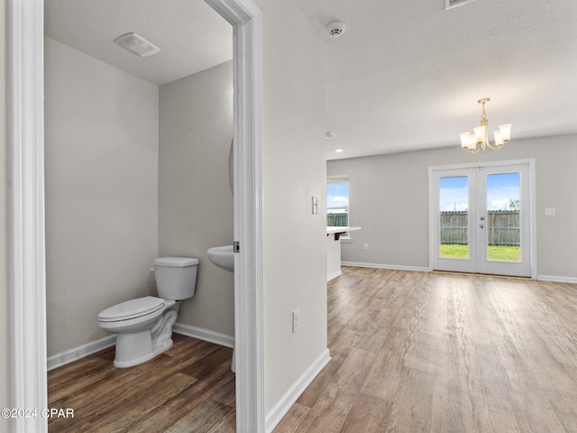 bathroom with french doors, toilet, hardwood / wood-style floors, and an inviting chandelier