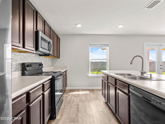 kitchen with backsplash, light wood-type flooring, sink, black appliances, and dark brown cabinets