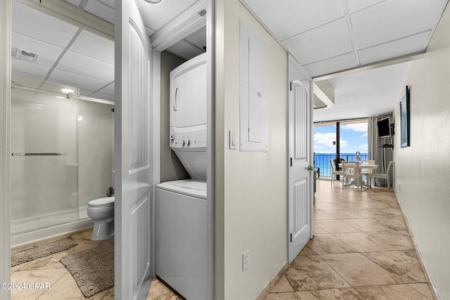 laundry room with light tile patterned flooring and stacked washer / drying machine